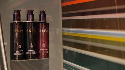 two bottles of espa shampoo are placed on a shelf , with a colorful background of hair care products at Village Hotel Liverpool