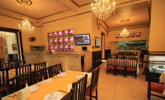 a well - lit restaurant with multiple dining tables and chairs , as well as a television mounted on the wall at Hotel Luna