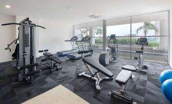 a well - equipped gym with various exercise equipment , including treadmills and weight machines , in front of a large window at Best Western I-City Shah Alam