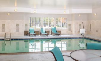 a large indoor swimming pool surrounded by lounge chairs , where people are relaxing and enjoying their time at Residence Inn Largo Medical Center Drive