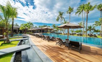 a resort with a large pool surrounded by lounge chairs and umbrellas , providing a relaxing atmosphere for guests at La Vela Khao Lak