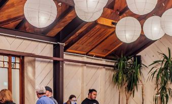 a group of people are sitting at tables in a restaurant with hanging white lanterns at The Cambridge Hotel