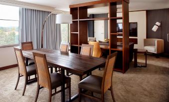 a wooden dining table surrounded by chairs in a room with a window and a bookshelf at Raleigh Marriott Crabtree Valley