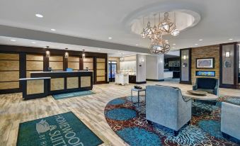 a hotel lobby with a reception desk , a large rug on the floor , and several chairs at Homewood Suites by Hilton Hamilton