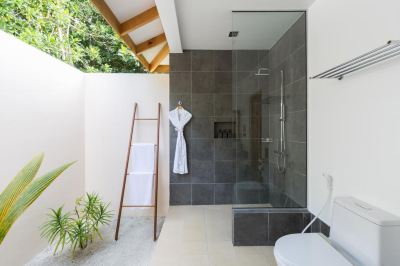 a modern bathroom with a walk - in shower , a toilet , and a wooden ladder leading up to the shower area at Vilamendhoo Island Resort & Spa