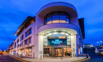 a modern building with a curved roof and large windows is illuminated by blue lights at The Ellison