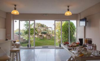 a dining room with a large dining table and chairs , surrounded by windows that offer a view of a garden at Sofi