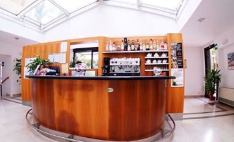 a bar with a curved wooden counter and shelves filled with various items , including bottles and glasses at Hotel Le Palme