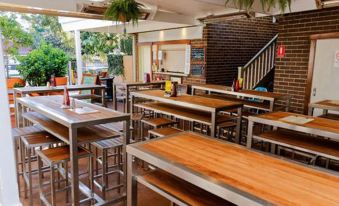 a large , empty restaurant with wooden tables and chairs set up in an outdoor area at Captain Cook Hotel