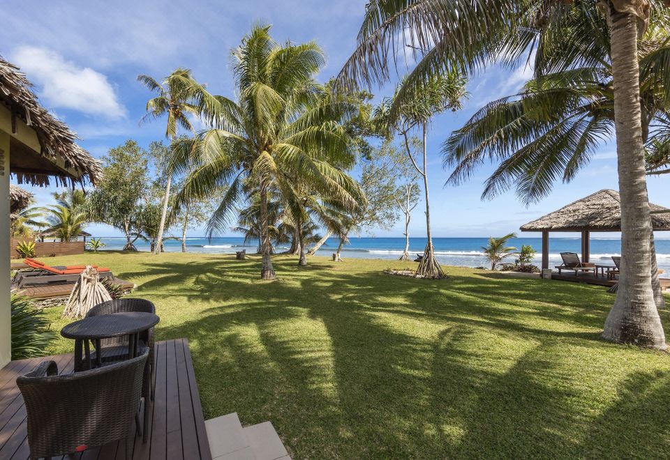 a tropical setting with palm trees , grassy lawn , and ocean view from a deck overlooking the water at Eratap Beach Resort
