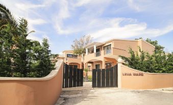 a modern , two - story building with orange walls and black fences , surrounded by trees and blue sky at Lena Mare Boutique Hotel