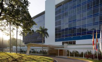a large , modern building with a blue and white facade is surrounded by trees and grass at Marriott Maracay Golf Resort