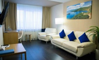 a modern living room with a white couch , blue pillows , and a painting on the wall at Norilsk