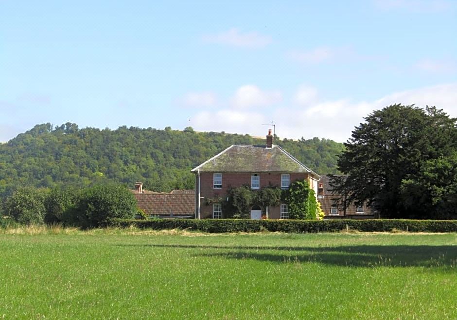 a large brick house with a red roof is surrounded by a green field and trees at Home Farm Boreham