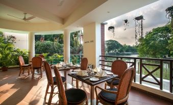 a dining area with a table and chairs , set for breakfast , overlooking a body of water at Hotel Grand Park Barishal