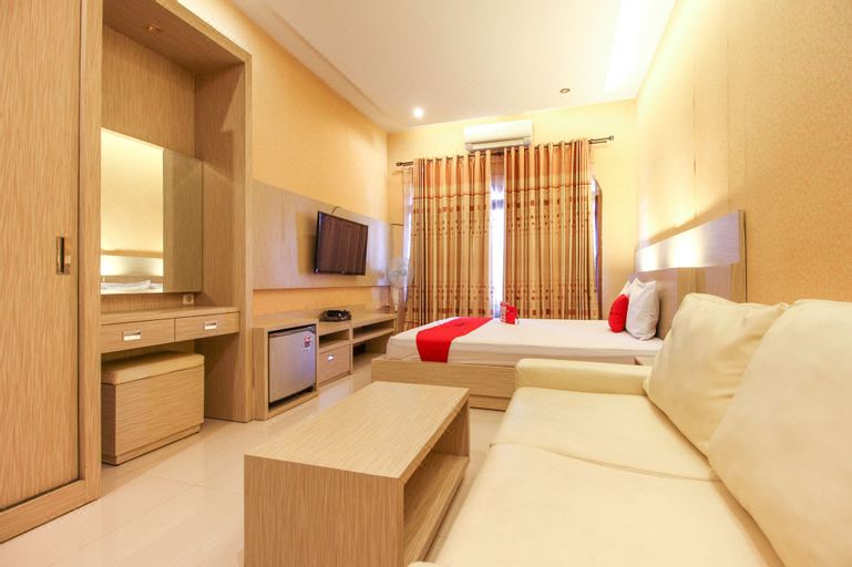 a modern hotel room with a bed , couch , and tv . also a dining table in the room at RedDoorz Near Candi Ratu Boko