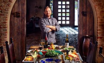 a man standing in front of a dining table with various dishes and wine glasses , ready to be served at Tubac Golf Resort & Spa