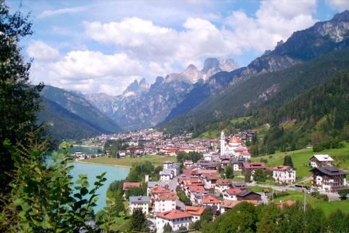 a picturesque mountain town with a lake in the background , surrounded by lush greenery and snow - capped mountains at Hotel Aurora