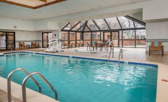 an indoor swimming pool surrounded by glass walls , with lounge chairs and tables set up for guests to relax at Courtyard by Marriott Fairfax Fair Oaks