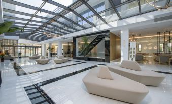 a modern , white interior with a large glass ceiling and black and white checkered flooring at Myrion Beach Resort & Spa - Adults Only