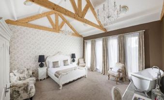 a white bedroom with a large bed , a couch , and a chandelier hanging from the ceiling at The Cook and Barker Inn