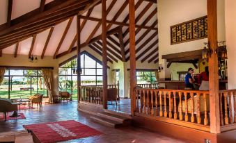 a spacious hotel lobby with high ceilings , wooden beams , and large windows , providing a comfortable environment for guests at Sweetwaters Serena Camp