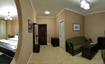 a spacious living room with beige walls , wooden doors , and a green couch , accompanied by a door leading to another room at Holiday Village