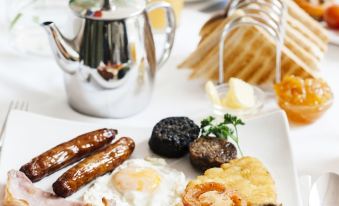 a delicious breakfast plate with sausages , eggs , toast , and various vegetables , accompanied by a cup of coffee at Brandon House Hotel