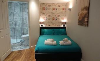 a bedroom with a bed , two pillows , and towels on it , along with a bathroom visible through an open door at BexLet