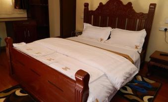 a wooden bed with white sheets and a dark wood headboard is shown in a hotel room at Lalanasi Lodge