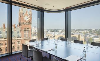 a conference room with a large table surrounded by chairs and a view of the city through a window at The Standard London