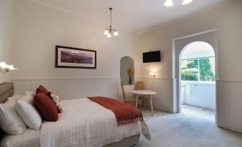 a bedroom with a bed , table , and chairs is shown with an open doorway leading to a balcony at Windarra on High