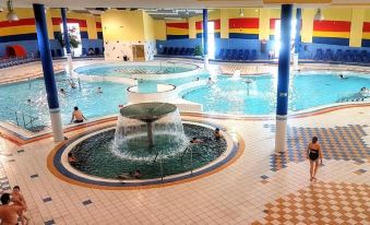 a large indoor swimming pool with people swimming and a fountain in the center , surrounded by colorful walls at Hotel 99