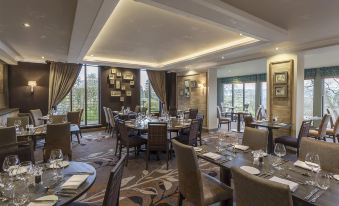 a modern restaurant with multiple dining tables , chairs , and large windows , giving it a view of the city at Castle Green Hotel in Kendal, BW Premier Collection