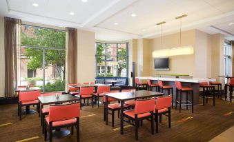 a restaurant with several tables and chairs , a television mounted on the wall , and large windows at Courtyard by Marriott Boston Brookline