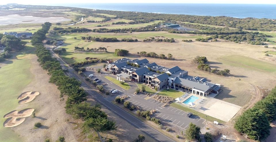 an aerial view of a large building with a swimming pool and surrounding greenery near the ocean at Barwon Heads Resort