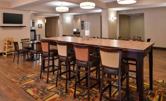 a hotel lobby with a long dining table and several chairs arranged around it , creating a comfortable seating area at Wingate by Wyndham Steubenville