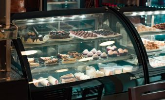 a display case filled with various pastries and desserts , including cakes , donuts , and cupcakes , in a bakery setting at Nova Hotel