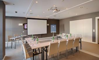 a conference room with a long table , chairs , and a projector screen , ready for a meeting at NH Padova