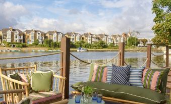 a wooden deck with a couch and chairs overlooking a body of water , creating a serene and inviting atmosphere at The Mitre, Hampton Court