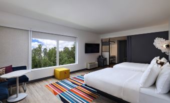 a hotel room with a large bed , a tv , and a colorful rug on the floor at Aloft Little Rock West