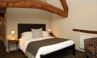 a neatly made bed with a wooden headboard and footboard is shown in a bedroom at The Blue Boar