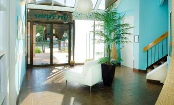 "a hotel lobby with a white couch , potted plants , and a large sign that reads "" sunlit "" on the wall" at Thriftlodge Kingston