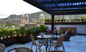 a rooftop patio with a view of the city , featuring several chairs and a table at Hotel Perlatto
