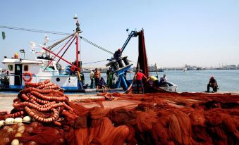 a group of people on a boat are working near a pile of red rope at Hotel Neptuno