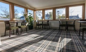 a large room with multiple dining tables and chairs , some of which are occupied by people at Castletown Hotel