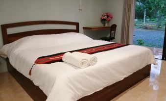 a neatly made bed with white sheets and a red striped blanket , positioned next to a window with a view at Piamsuk Resort