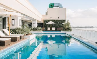 a large swimming pool is surrounded by a white building and lounge chairs with umbrellas at Rizal Park Hotel