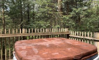 a brown tarp covering a hot tub on a deck , surrounded by trees and a wooden fence at Opossum Creek Retreat