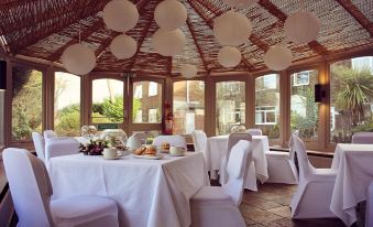 a dining room with white tables and chairs , white tablecloths , and a canopy overhead at Birch Hotel